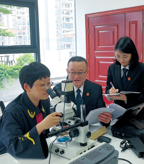 张姝法官（左一）与技术调查官付雄（左二）在实验室通过显微镜比对涉案芯片。